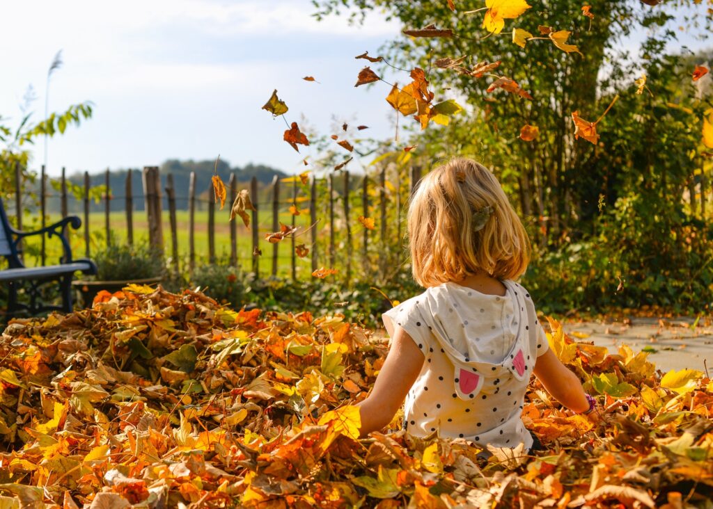 A young girl playing in fallen leaves